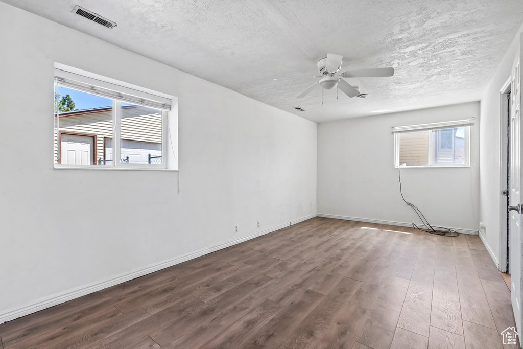 Unfurnished room with a ceiling fan, wood finished floors, a textured ceiling, and baseboards
