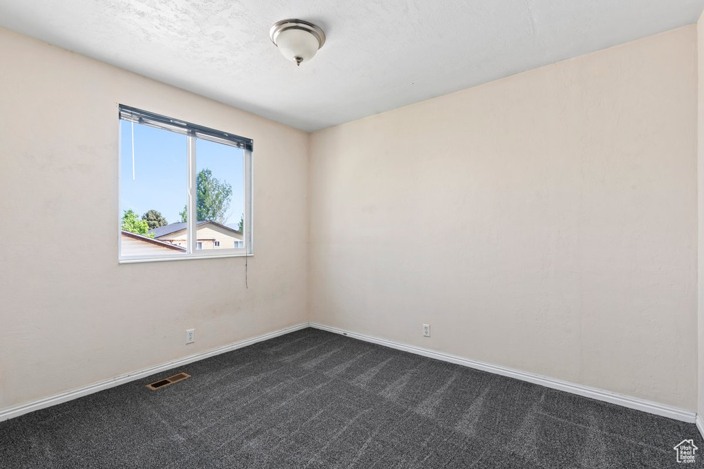 Spare room with dark carpet and baseboards