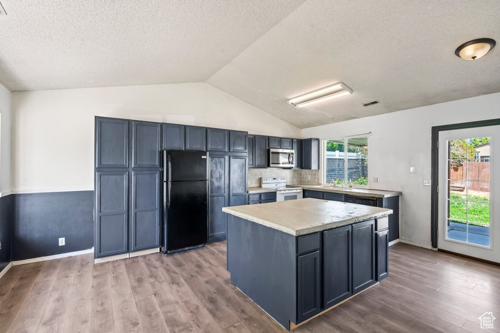 Kitchen featuring white range with electric stovetop, freestanding refrigerator, stainless steel microwave, light countertops, and light wood-style floors