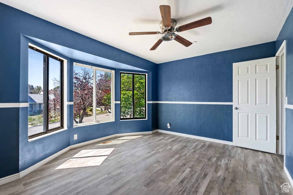 Empty room featuring wood finished floors, a ceiling fan, and baseboards
