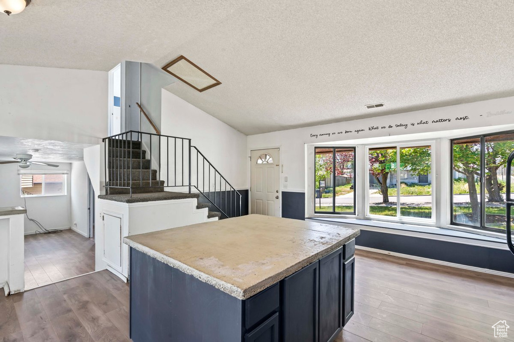 Kitchen with wood finished floors, a textured ceiling, a ceiling fan, lofted ceiling, and baseboards