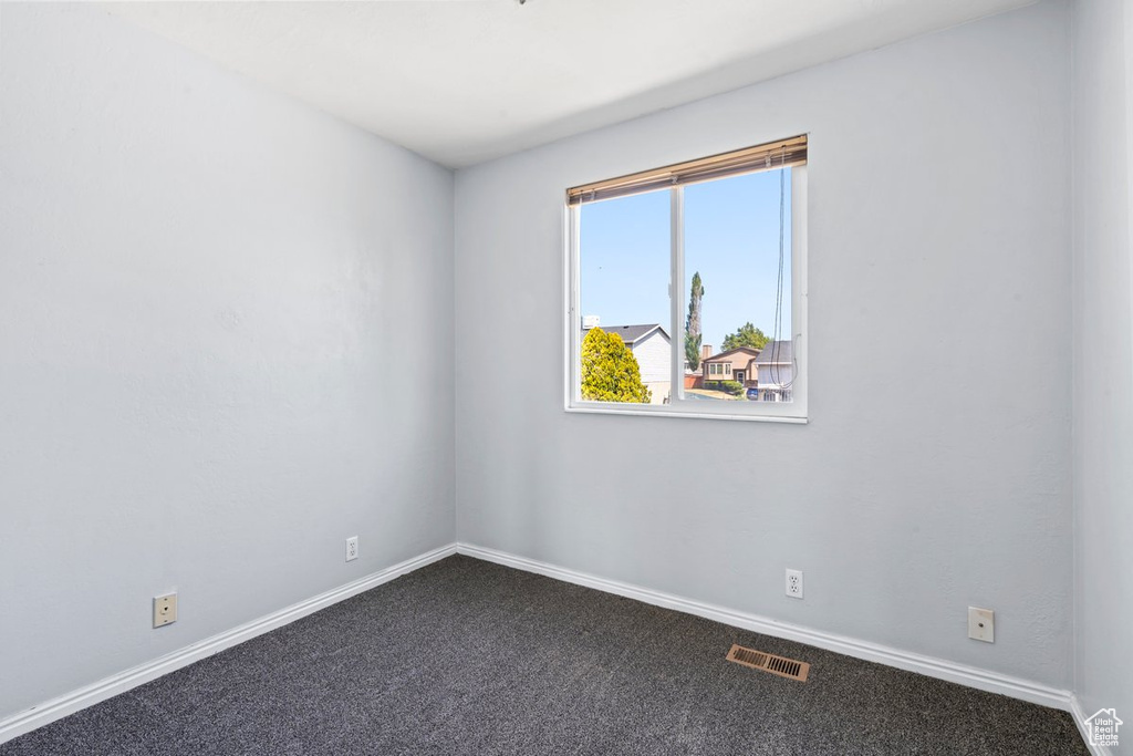 Unfurnished room featuring dark carpet and baseboards