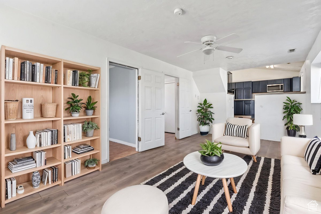 Living area featuring a ceiling fan, light wood-style floors, and baseboards