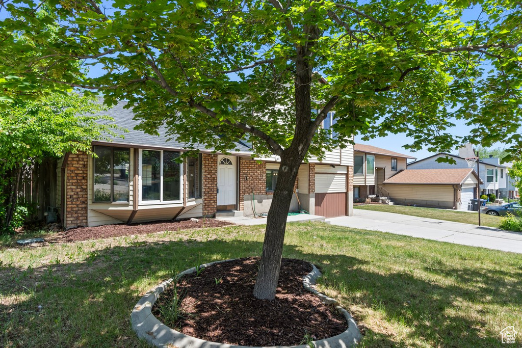 Tri-level home with brick siding and a front yard