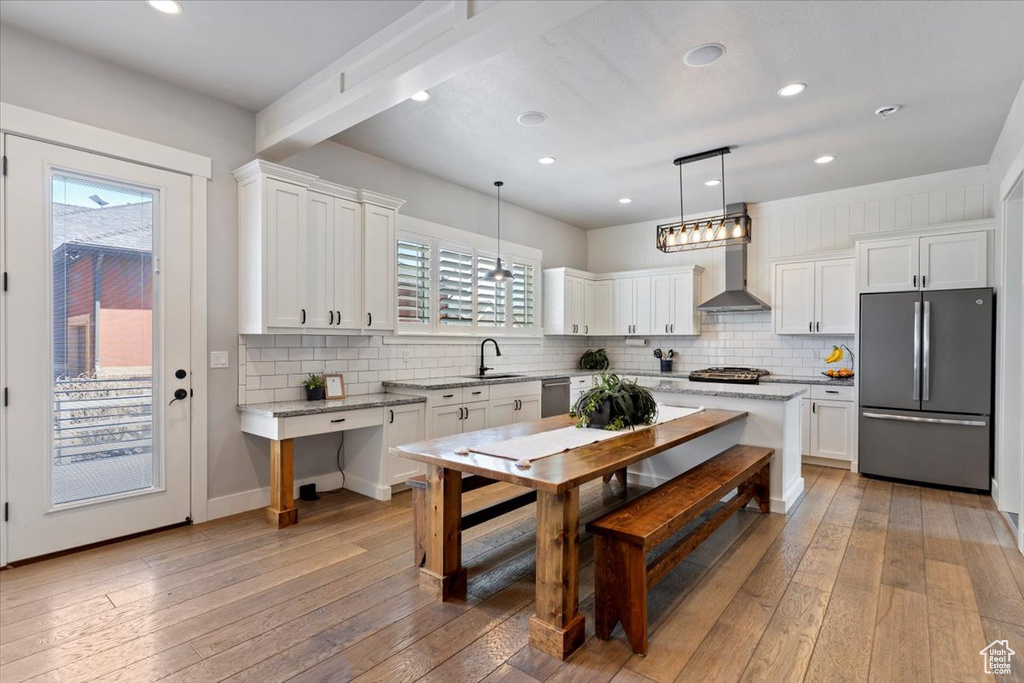 Kitchen with stainless steel appliances, wall chimney range hood, a sink, backsplash, and recessed lighting