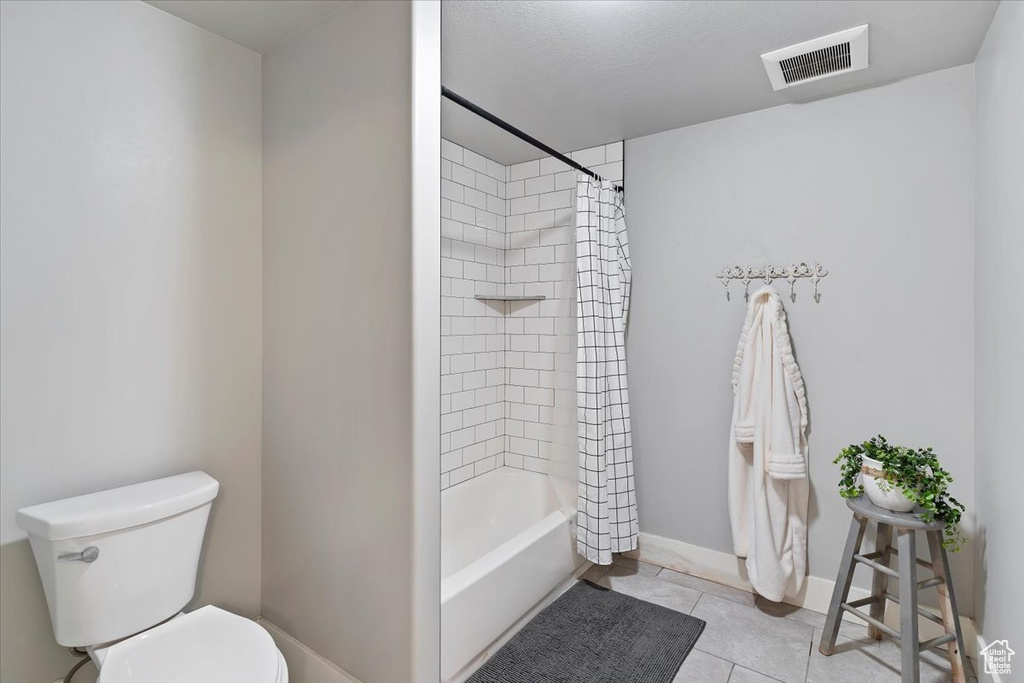 Bathroom with toilet, tile patterned flooring, shower / tub combo with curtain, and baseboards