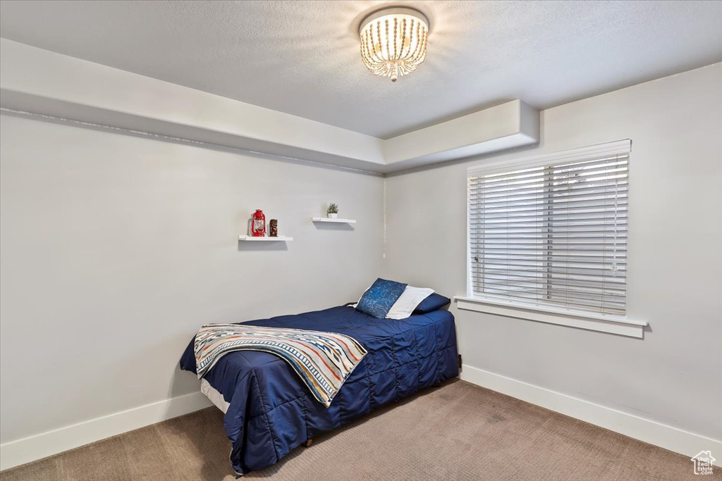 Carpeted bedroom featuring baseboards, a chandelier, and a textured ceiling