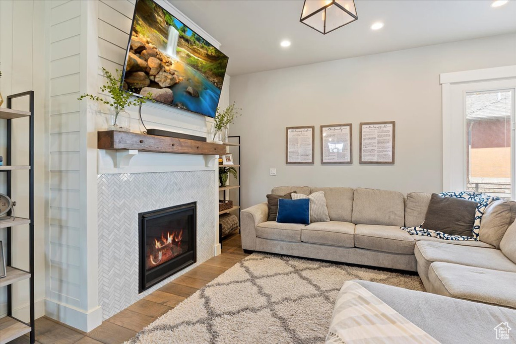Living room with wood finished floors, a tiled fireplace, and recessed lighting