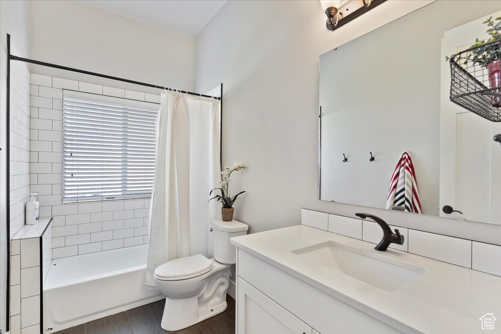 Bathroom featuring toilet, vanity, wood finished floors, and shower / tub combo