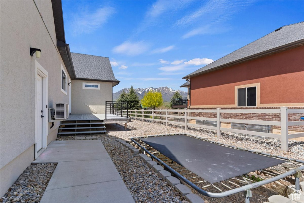 View of yard featuring a deck with mountain view, fence, and a cooling unit