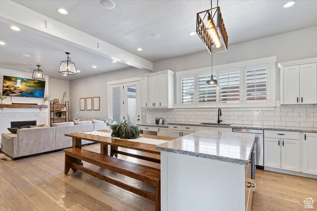 Kitchen featuring a sink, dishwasher, backsplash, beamed ceiling, and white cabinetry