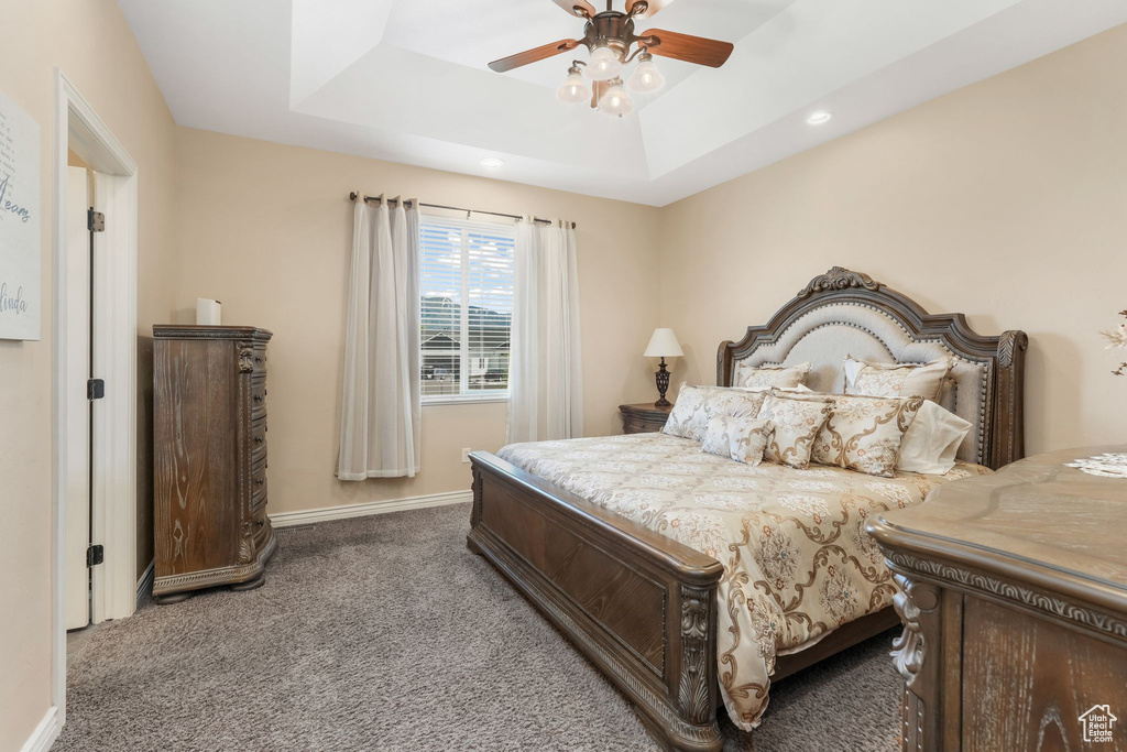 Carpeted bedroom with a tray ceiling, recessed lighting, baseboards, and ceiling fan