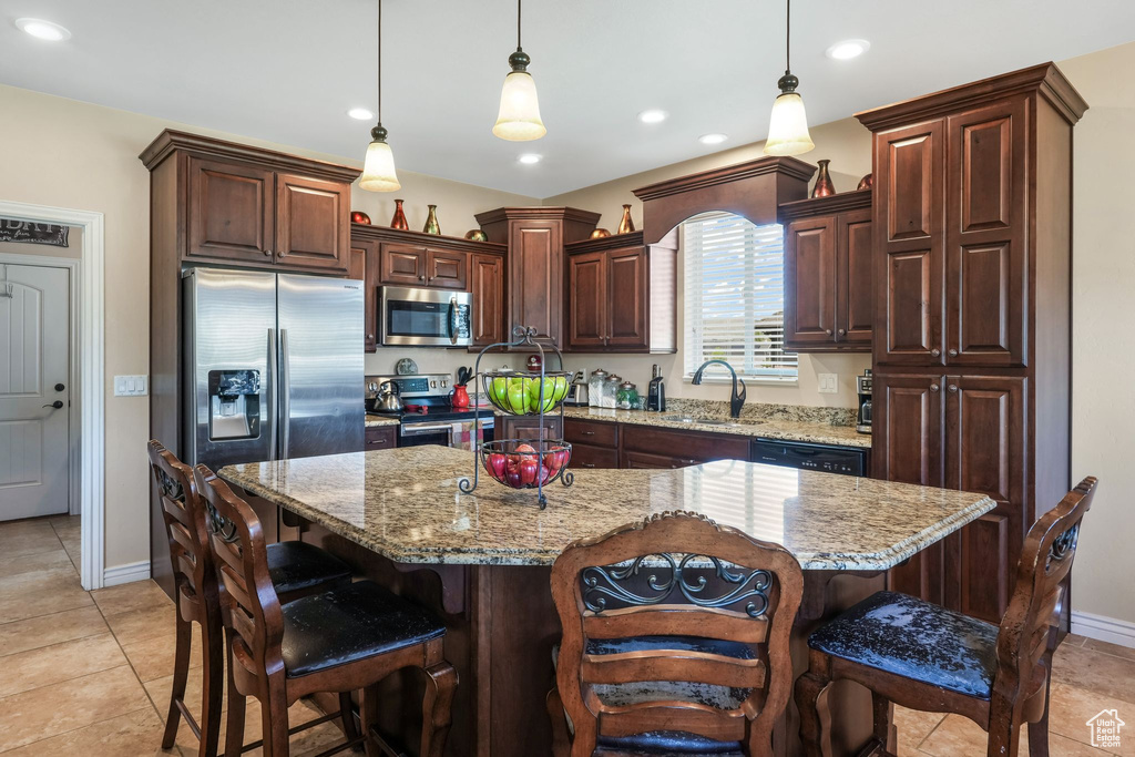 Kitchen with stainless steel appliances, a breakfast bar area, pendant lighting, baseboards, and recessed lighting