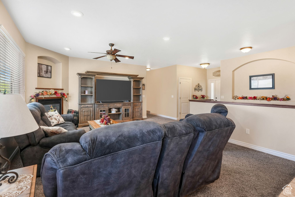 Living room with ceiling fan, carpet, baseboards, a glass covered fireplace, and recessed lighting