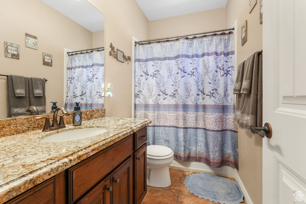Bathroom with toilet, vanity, tile patterned flooring, and shower / tub combo
