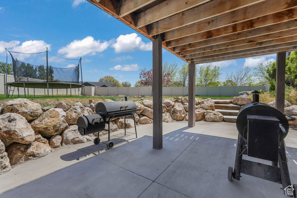 View of patio with a trampoline and a fenced backyard