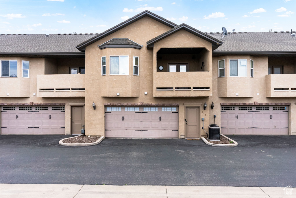 Back of house featuring stucco siding, an attached garage, and a balcony