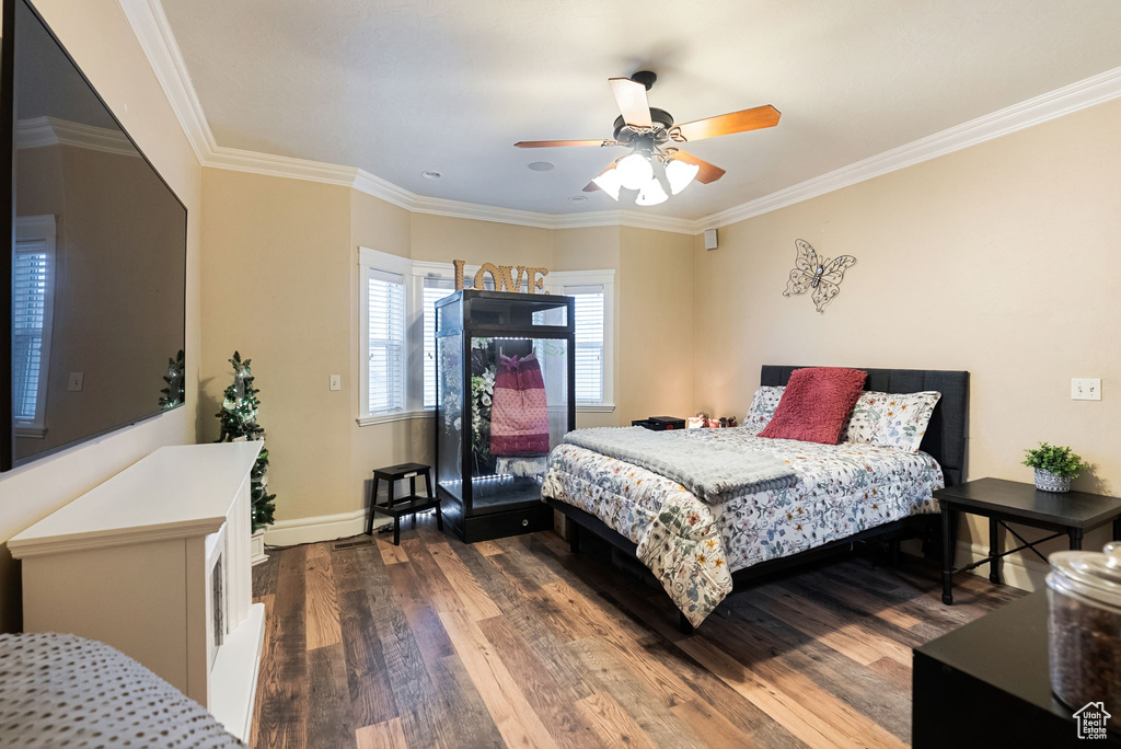 Bedroom with dark wood-type flooring, baseboards, ornamental molding, and a ceiling fan