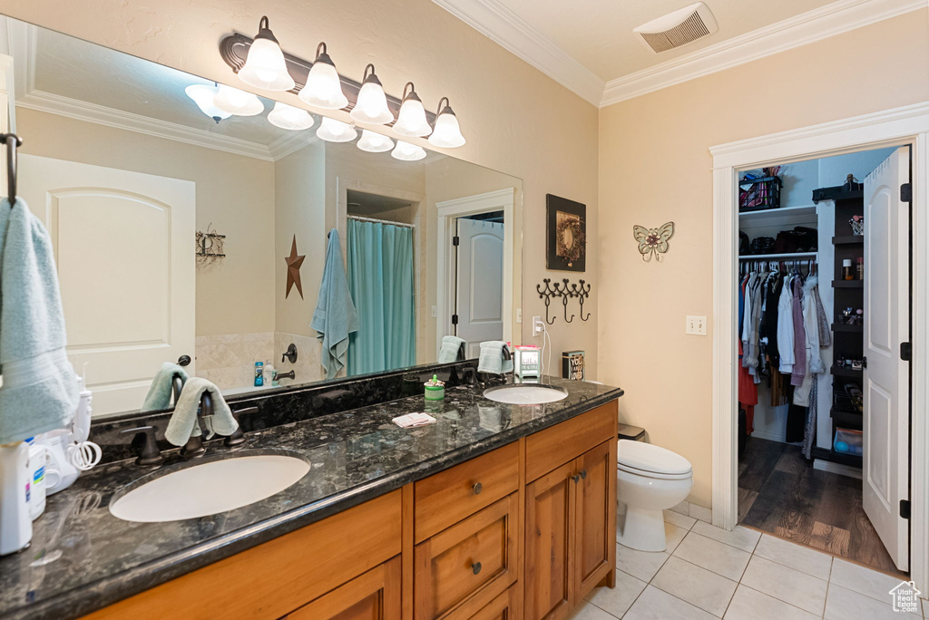 Full bathroom with crown molding, tile patterned floors, double vanity, a shower with shower curtain, and toilet