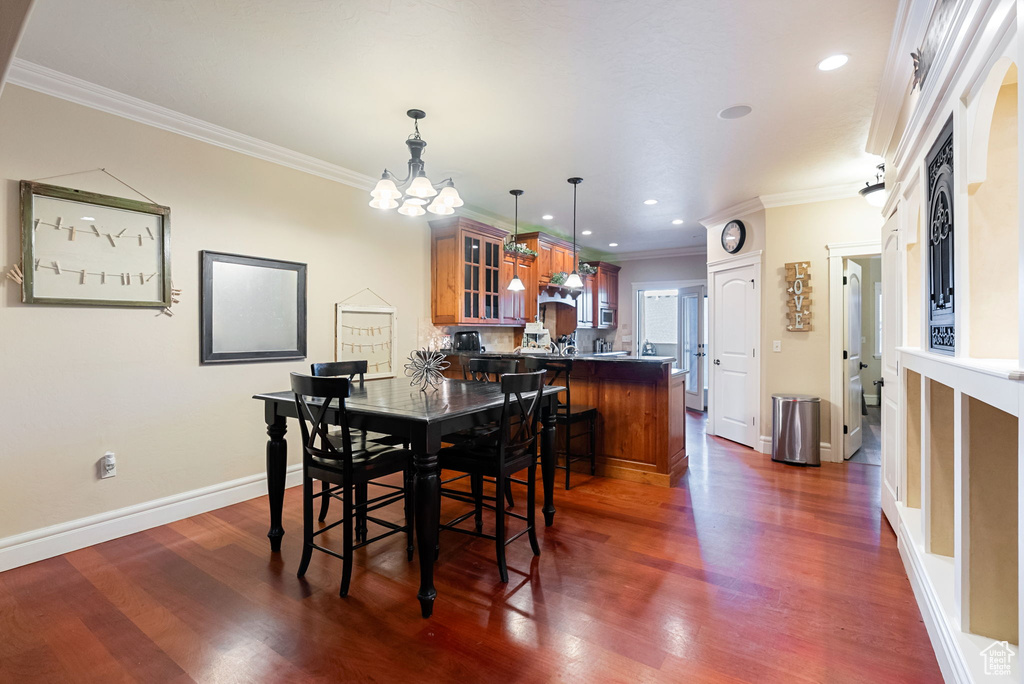 Dining area featuring a chandelier, ornamental molding, dark wood-style flooring, baseboards, and recessed lighting