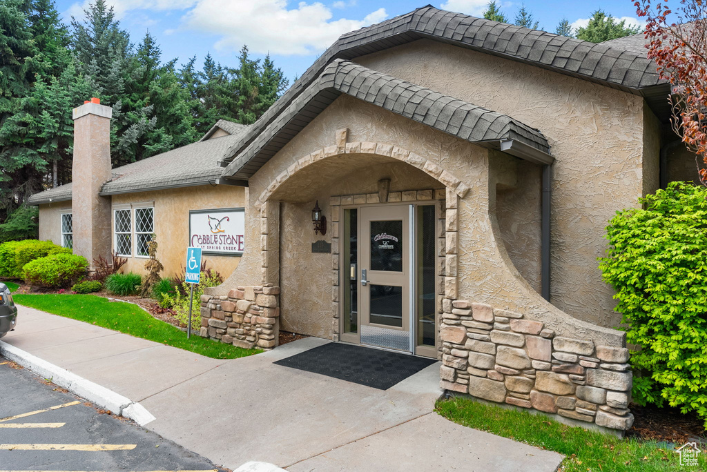 Doorway to property with stone siding, stucco siding, and a chimney