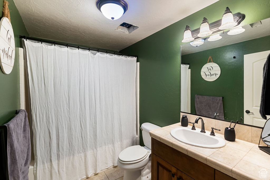Full bathroom featuring vanity, toilet, tile patterned flooring, and shower / tub combo with curtain