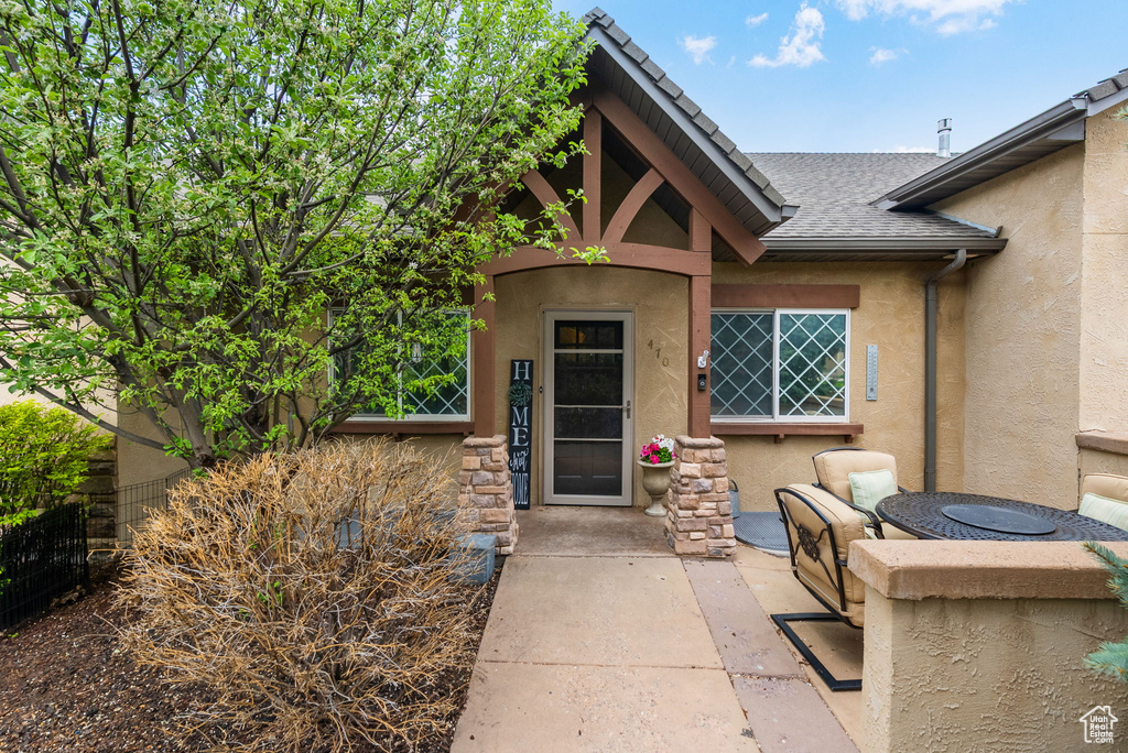 Entrance to property with stucco siding and roof with shingles