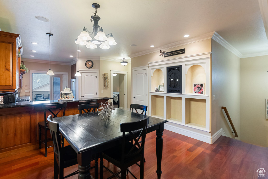 Dining room featuring dark wood-style flooring, a chandelier, recessed lighting, and ornamental molding