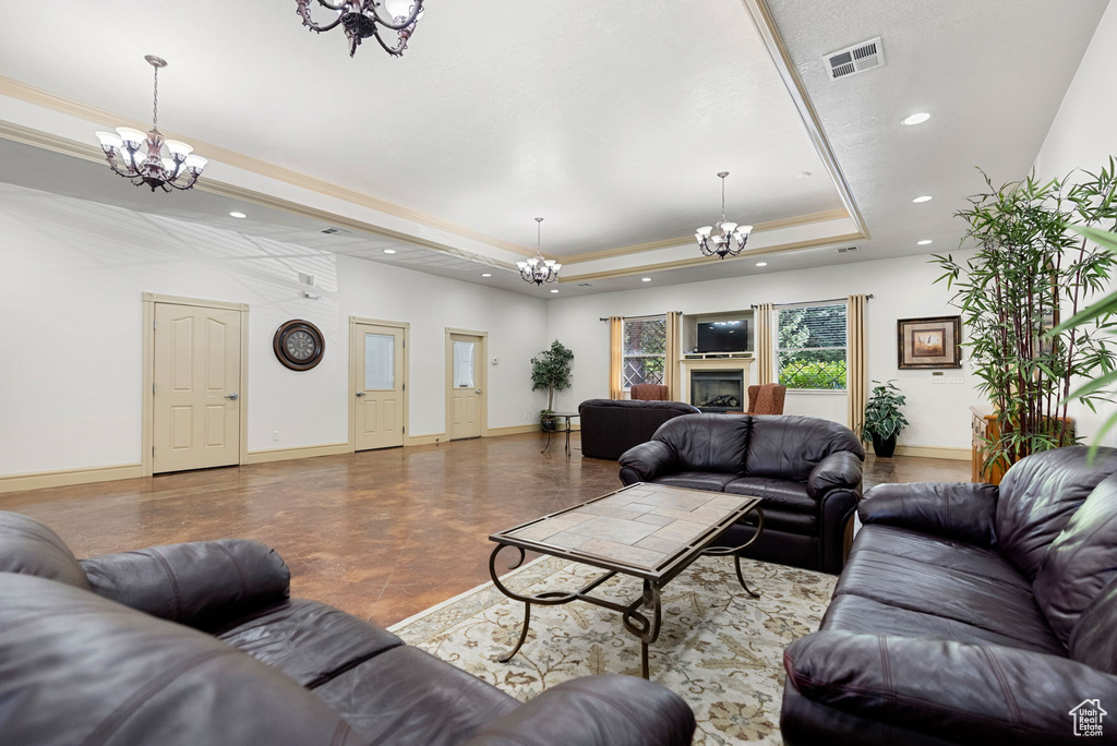 Living area featuring a chandelier, a raised ceiling, recessed lighting, and baseboards