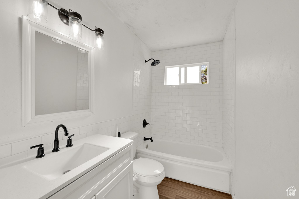 Full bathroom with wood finished floors, toilet, tub / shower combination, and vanity
