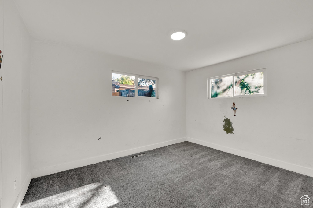 Spare room featuring dark carpet and baseboards