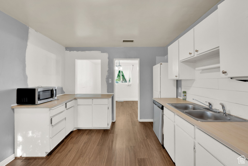 Kitchen with stainless steel appliances, a sink, baseboards, and light countertops