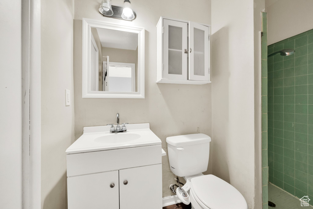 Full bathroom featuring toilet, tiled shower, and vanity