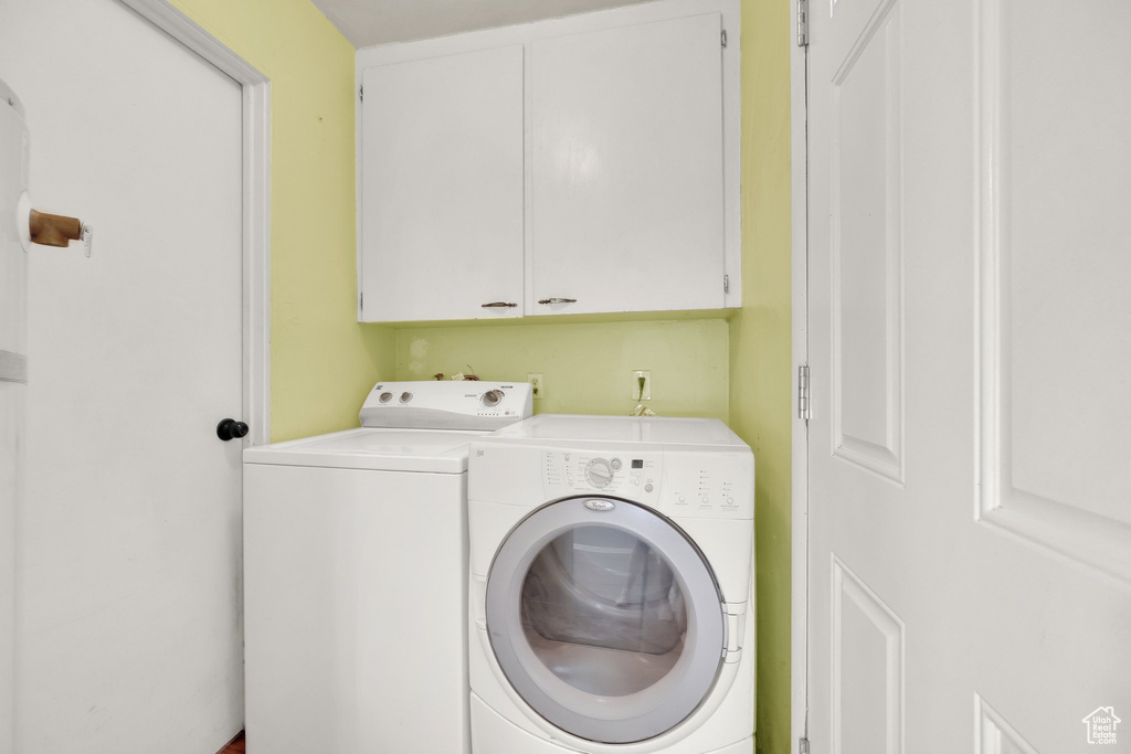 Clothes washing area featuring separate washer and dryer and cabinet space