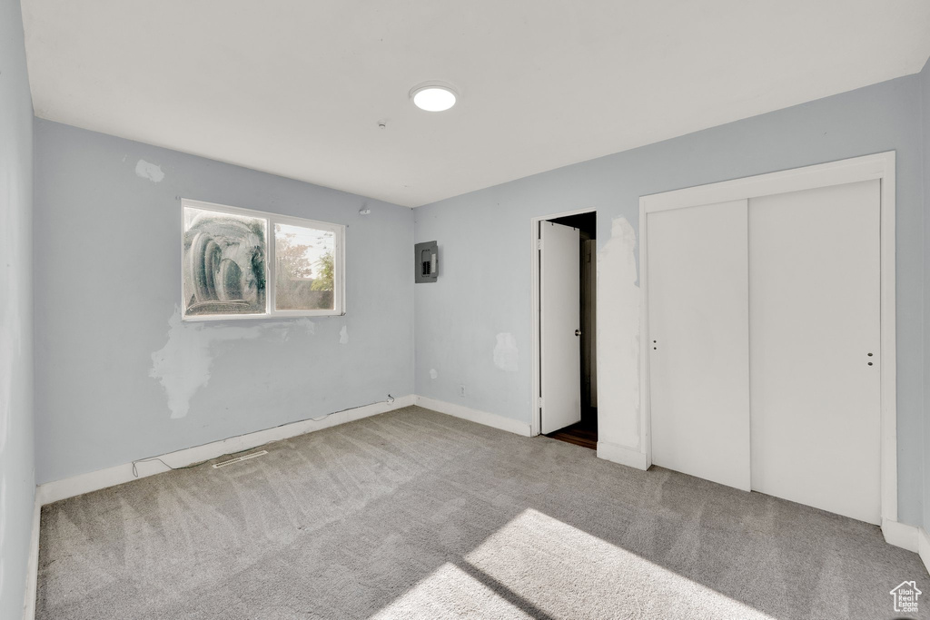 Unfurnished bedroom featuring carpet floors, a closet, baseboards, and electric panel