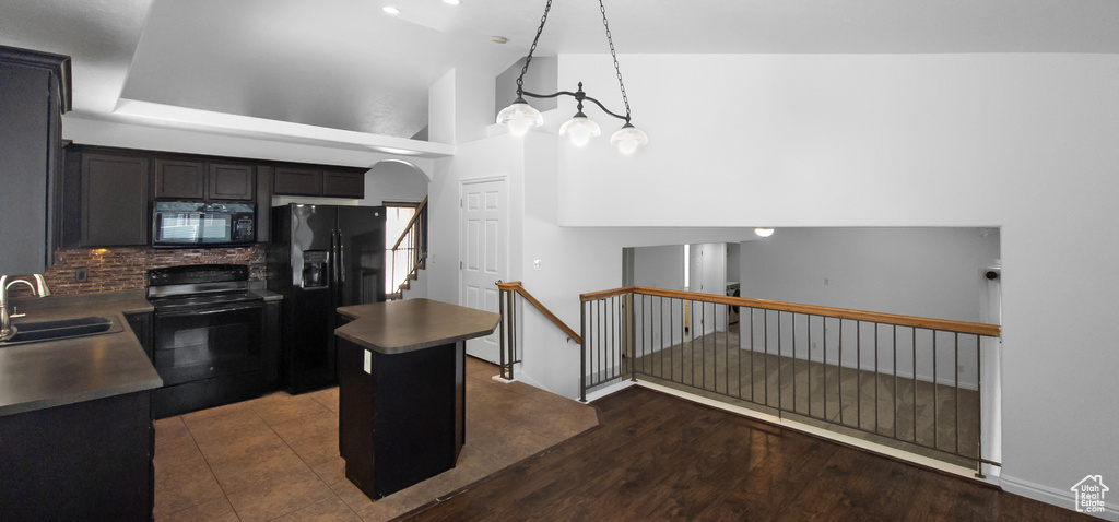 Kitchen with black appliances, a sink, a kitchen island, decorative backsplash, and dark countertops