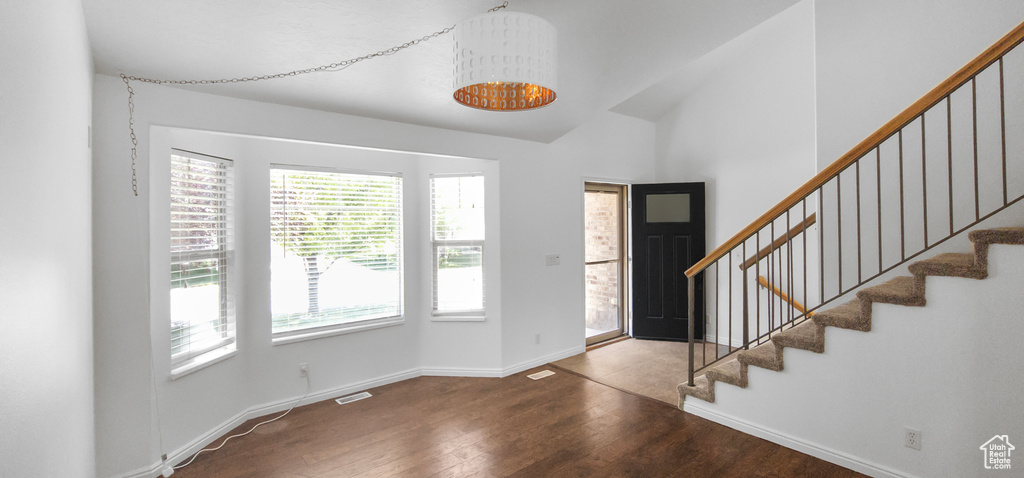 Entrance foyer featuring wood finished floors, stairway, baseboards, and high vaulted ceiling