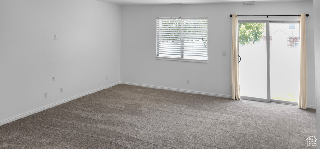 Carpeted spare room featuring baseboards