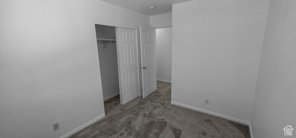 Unfurnished bedroom featuring carpet flooring, baseboards, and a closet