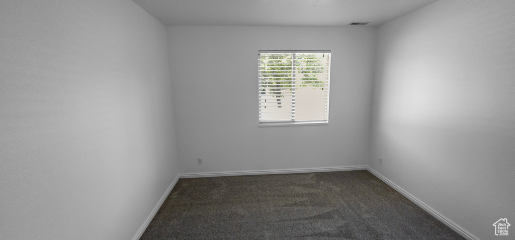 Unfurnished room featuring dark carpet and baseboards