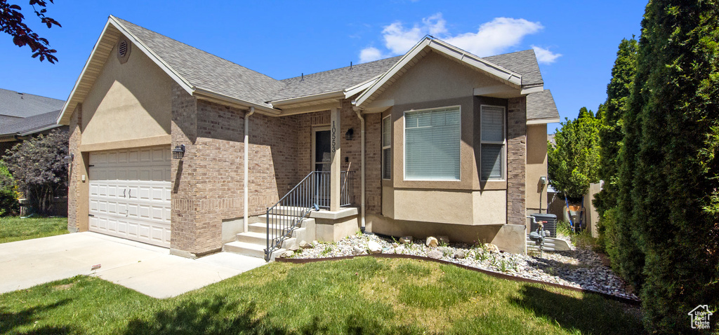 Ranch-style home with an attached garage, concrete driveway, stucco siding, and a front lawn