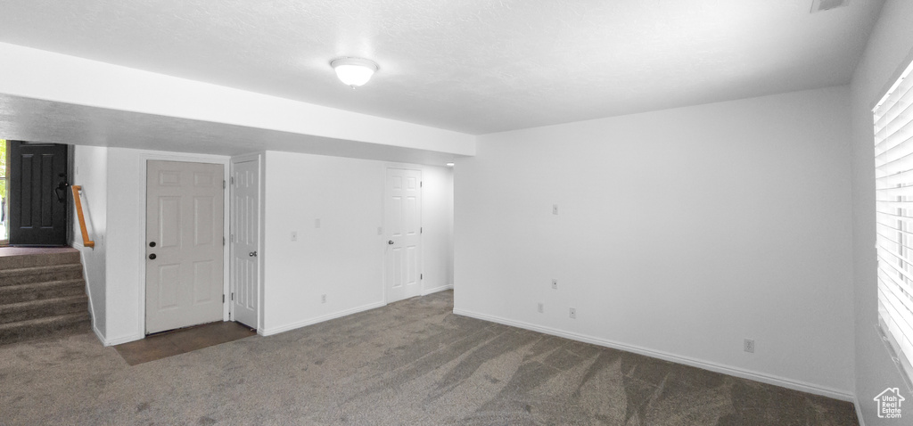 Carpeted empty room featuring baseboards and stairway