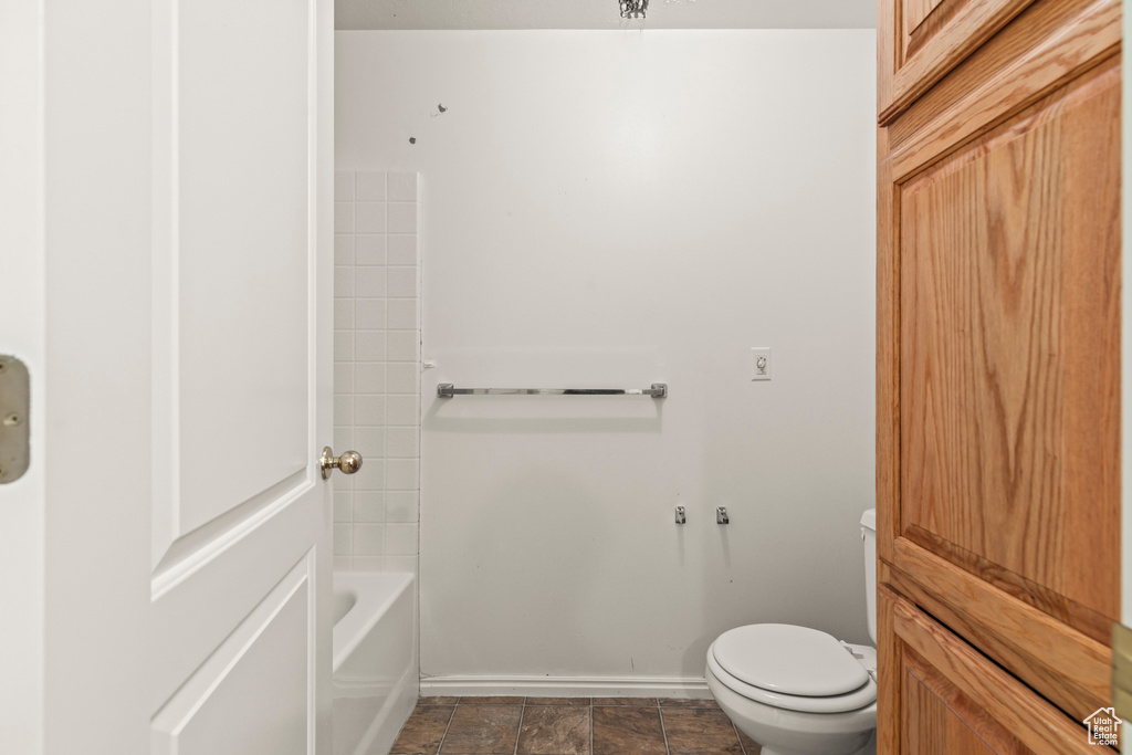 Bathroom with baseboards, toilet, and shower / bath combination