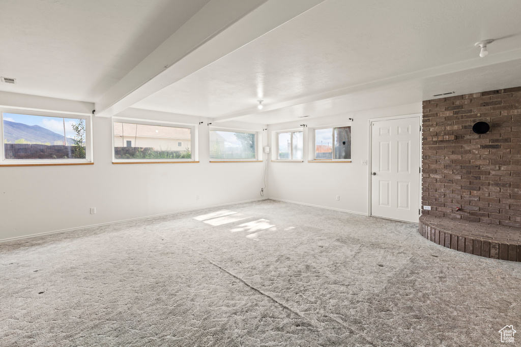 Unfurnished living room with carpet, plenty of natural light, and baseboards
