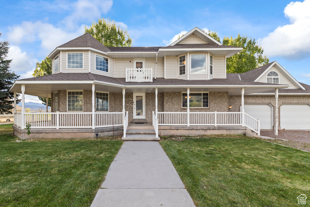 View of front facade with a porch, brick siding, and a front yard