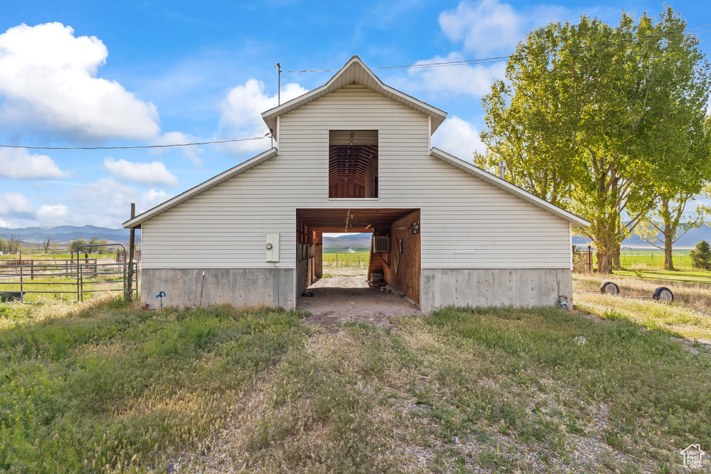Rear view of house featuring a barn, fence, an outbuilding, a mountain view, and an AC wall unit