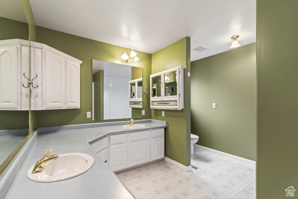Full bath featuring toilet, double vanity, baseboards, and tile patterned floors