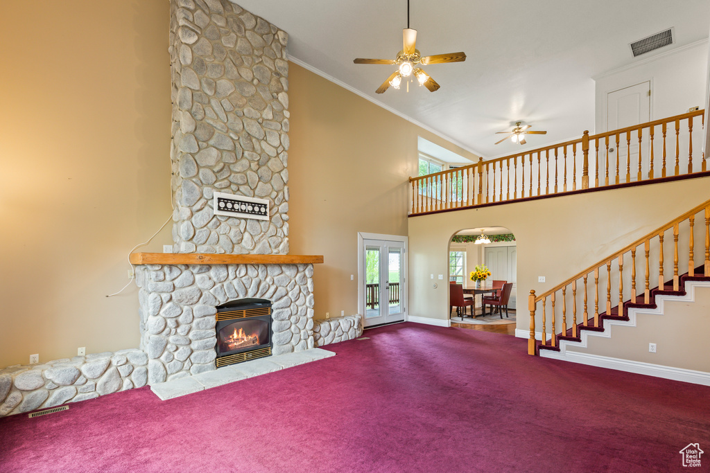 Unfurnished living room featuring high vaulted ceiling, ornamental molding, carpet, ceiling fan, and baseboards