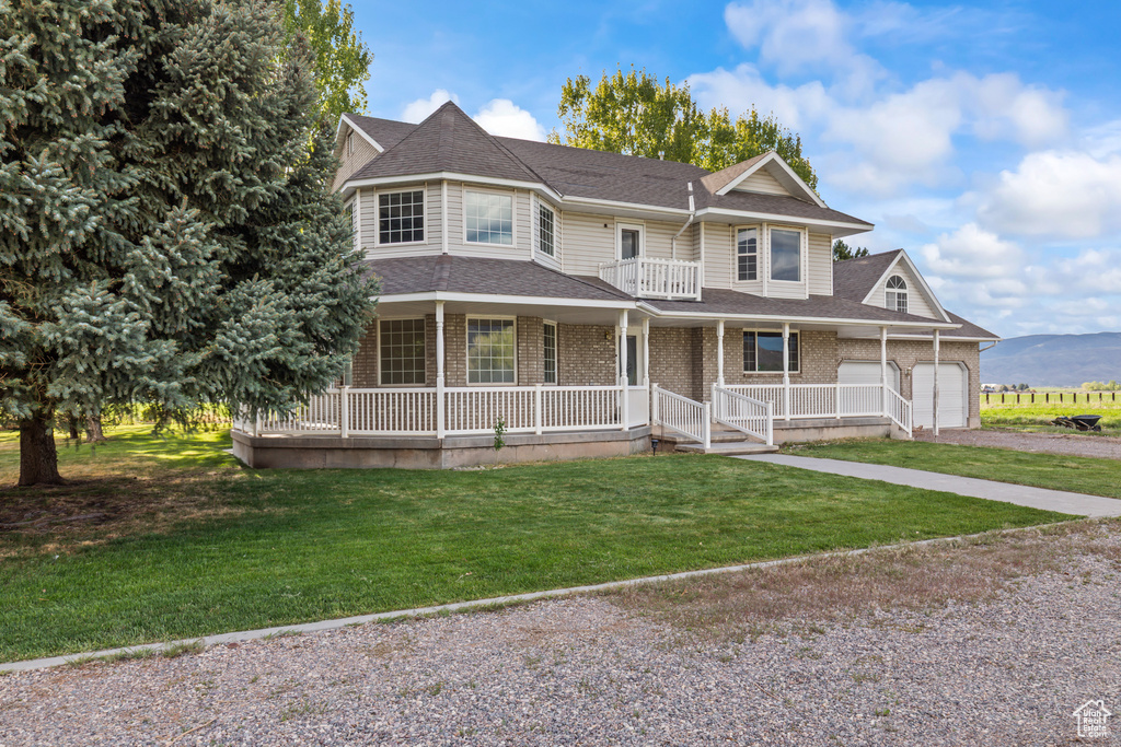 Victorian home with covered porch, gravel driveway, an attached garage, and a shingled roof