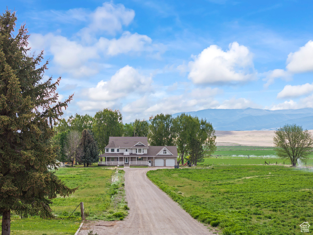 View of home\\\'s community featuring a yard, dirt driveway, a garage, and a water and mountain view